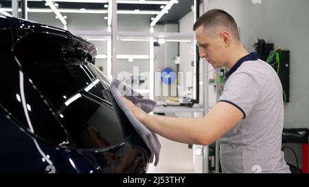 The master polishes the car. Vehicle detailing. A young man polishing his car. Master detailing center polishes a car body. Stock Photo