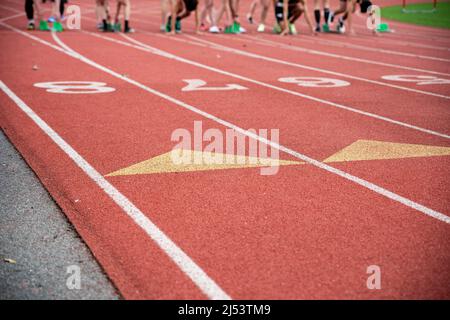 Runners are ready for the starting gun at their starting blocks. High energy closeup of athletic lane markings and numbers shot outdoors in natural li Stock Photo