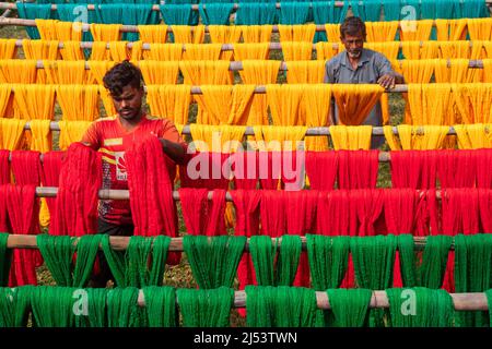 Narayanganj, Dhaka, Bangladesh. 20th Apr, 2022. Workers hang thousands of freshly dyed colorful threads on a wooden structure as they are being dried in the sunshine in Narayanganj, Bangladesh. Thousands of colorful threads create a palette of colors as workers hang them out to dry. The threads take a whole day to dry and stretch for hundreds of meters. Once dried, they are sold to wholesale markets. Each row of threads is priced for Â£2. The workers spend 12 hours in the fields during this process, earning Â£5 per day. (Credit Image: © Joy Saha/ZUMA Press Wire) Stock Photo