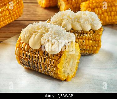 Grilled corn on cob with creamy topping and grated cotija cheese Stock Photo