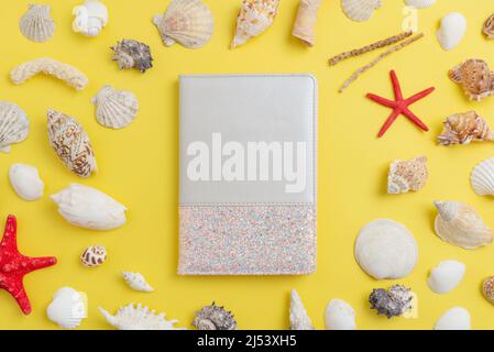 Decorative notebook on the table surrounded by shells and starfish with free space to promote the logo or text Stock Photo