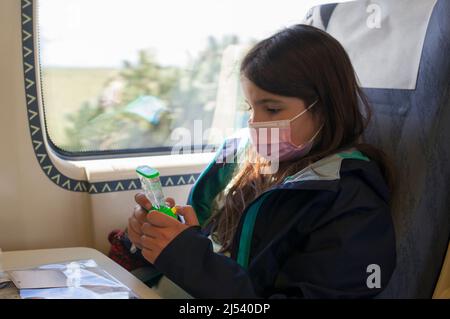 Little girl playing with water classic toy. Non-electronic entertainment for children in train Stock Photo