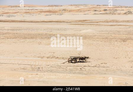 An abandoned, disintegrating wooden cart stands in the sand of the vast, arid Namib Desert Skeleton Coast, near Swakopmund, Namibia, south-west Africa Stock Photo