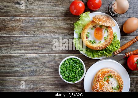 Baked buns stuffed with eggs and bacon on plates on a wooden background. Delicious and quick breakfast. Healthy eating concept. Food background with c Stock Photo