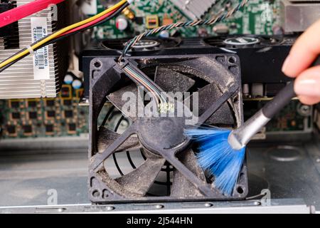 A computer master cleans the dust of the cooler of the ventilation of the system unit Stock Photo