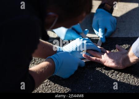 Offenbach, Germany. 20th Apr, 2022. Emergency forces detach the stuck hand of an activist from the 'Last Generation' from the roadway, where he had stuck himself in protest. Activists of the 'Last Generation' blocked the highway exit in Offenbach-Kaiserlei. Credit: Hannes P. Albert/dpa/Alamy Live News Stock Photo