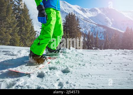 Close-up of a snowboarder legs with snow covered mountains Stock Photo