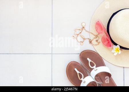 Beach accessories - sunglasses, straw hat, necklace with seashells and pearls, flip-flops, plumeria, flat lay with copy space Stock Photo