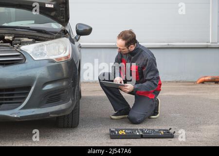 Mechanic with electronic tablet pc checking wheels and tires while working in the car repair center Stock Photo