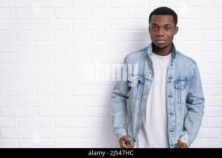 Portrait young handsome african black man wearing denim jeans jacket against brick with wall outdoors with copyspace. Stock Photo