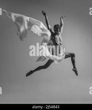 Desire. Black and white portrait of graceful muscled male ballet dancer dancing with fabric, cloth isolated on grey studio background. Grace, art Stock Photo