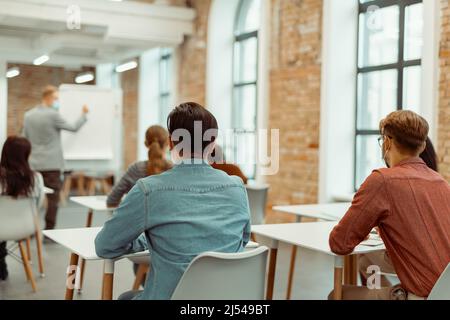 Teacher standing near flipchart during lecture to students Stock Photo