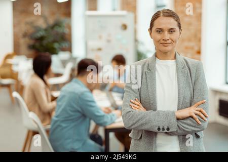 Smiling woman standing in a coworking space and clasped her hands Stock Photo