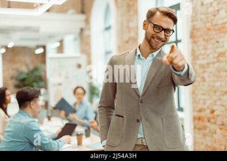 Man standing in the office with colleagues in the background Stock Photo