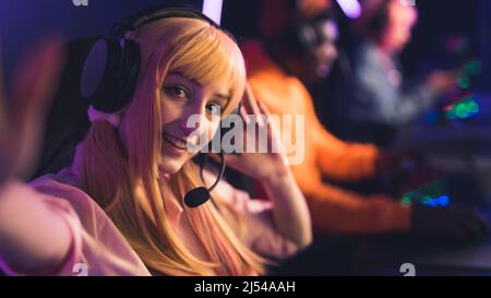 Selfie of young Caucasian female player in a wig and headphones smiling copy space players on the background . High quality photo Stock Photo