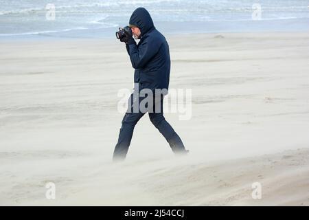 man in the storm on the sandy beach, Hurricane Eunice, Zeynep, 02/18/2022, Belgium, West Flanders, Nieuwpoort Stock Photo