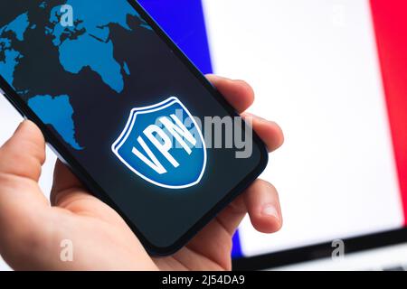 VPN in France. Secure and safe internet concept. Privacy. Hand with mobile phone and VPN application. Flag and laptop on the background photo Stock Photo