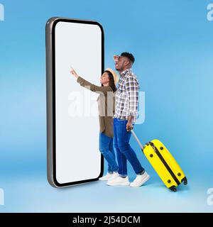 Black Tourists Couple Using Smartphone Touching Blank Screen, Blue Background Stock Photo