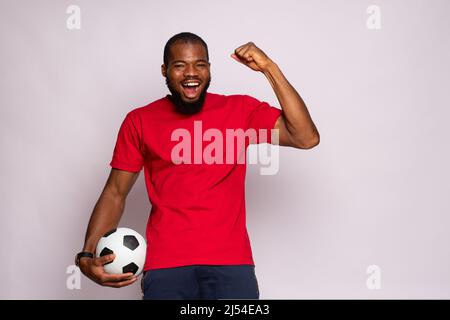 african man holding a soccer ball celebrates Stock Photo