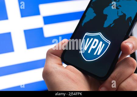 VPN in Greece. Secure and safe internet concept. Privacy. Hand with mobile phone and VPN application. Flag and laptop on the background photo Stock Photo