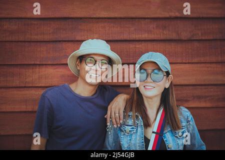 couples of middle age asian standing against brown wooden background Stock Photo