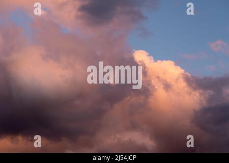 Colorful clouds in orange and purple colors against blue sky during sunset, detail from atmosphere Stock Photo