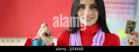 Young woman holds plastic credit card and shopping bags Stock Photo