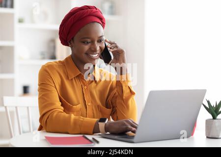 Positive muslim black woman working on laptop at office Stock Photo