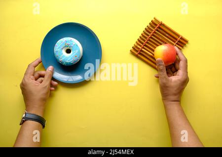 hand holding donuts and apple on hand on blue background  Stock Photo