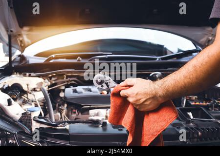 Auto mechanic hand holding wrench and red cloth to repair car with car engine background Stock Photo