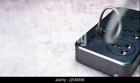 Adapter power plug with a USB port and multiple socket for mobile phone charging or home electric appliance on the cement floor Stock Photo
