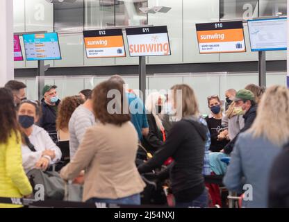 Travellers wait in line at a Sunwing Airlines check-in desk at Trudeau  Airport in Montreal, Wednesday, April 20, 2022. The federal transport  minister's office says issues being faced by Sunwing travellers from
