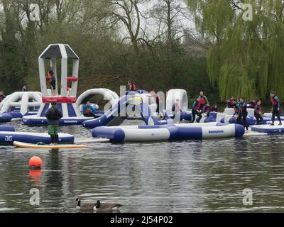 Group of schoolchildren enjoying Lagoon Wipeout inflatable obstacle course beams demolition balls humps basher Holme Pierrepont Country Park Stock Photo