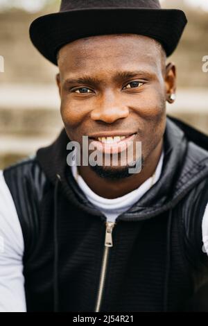Portrait of a smiling handsome young black male wearing a black hat Stock Photo