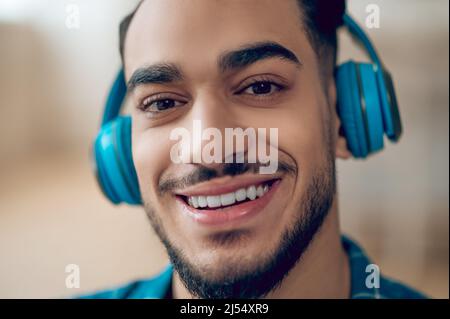 Smiling young man in a blue tshirt and with headphones Stock Photo