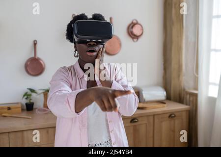 African woman in pink clothes in vr glasses looking excited Stock Photo