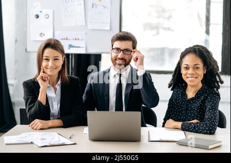 Teamwork, collaboration concept. Multiracial influential business people in formal wear look at the camera, smiling. Elegant creative colleagues sitting in modern office, working together on project Stock Photo