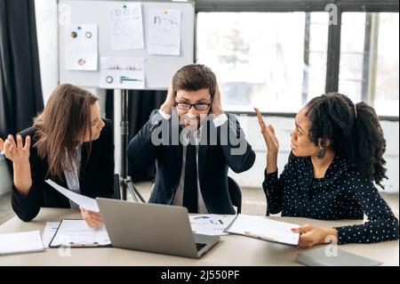 Conflict between employees. Business partners of different nationalities have a disagreement, cannot find a compromise, argue emotionally, sitting at a table in the office, shouting Stock Photo