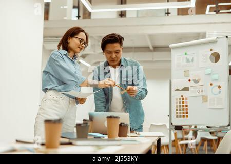 Two colleagues standing in the office and holding documents Stock Photo