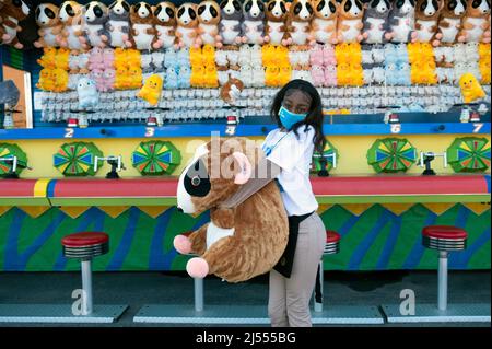 A Brooklyn teenager begins her summer job by working Spring weekends at a Luna Park skills game. In Coney Island, Brooklyn, New York City. Stock Photo