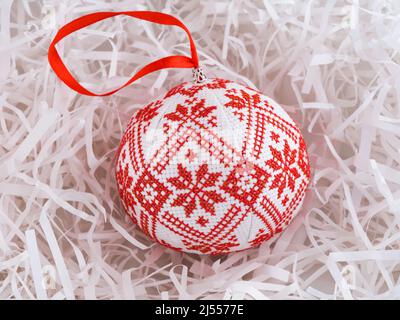 Cross stitched christmas ornament on white shredded wrapping paper background. Christmas ornament made by me. Stock Photo