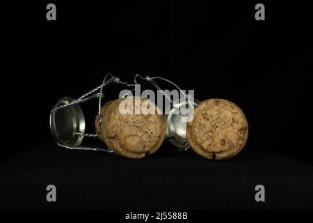 two sparkling wine corks and wire cages isolated on a black background Stock Photo