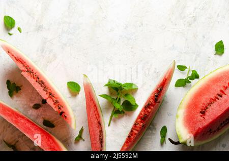 Slices of watermelon with mint leaves on a light background with copy space. Top view. Stock Photo