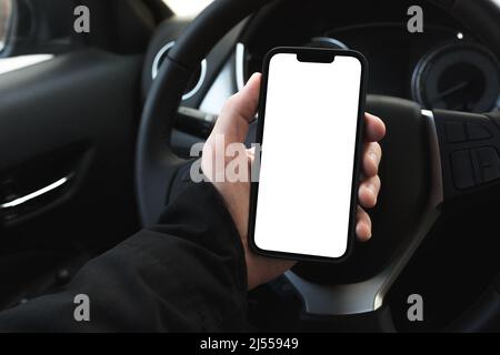 Male driver using smartphone in the car, blank white screen of mobile device as copy space, selective focus Stock Photo