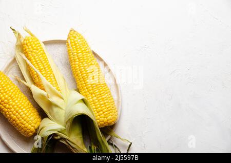 Three corncobs in a plate on a white background. Stock Photo