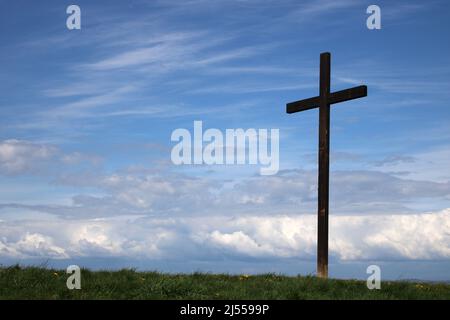 Wooden Easter Cross at Lane Ends Amenity Area, Pilling, Lancashirewith blue sky and white wispy clouds behind. Stock Photo