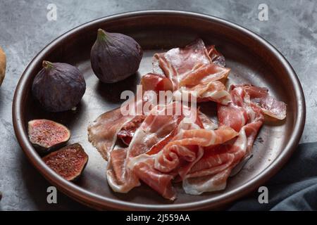 Jamon with figs and a baguette with cream cheese on the dining table, appetizer for wine, Spanish cooking. Stock Photo