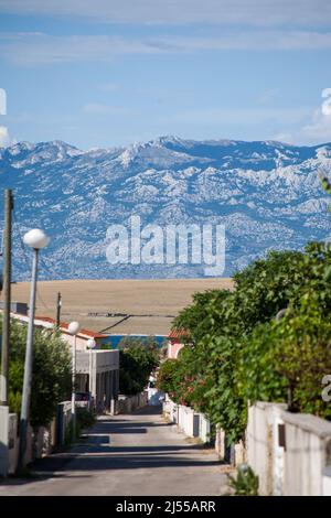 A small alley towards the sea in the apartment complex Lučica on the island of Vir, Croatia. View of the sea and the mountains. Stock Photo