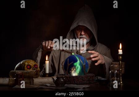 Medieval wizard cast magic with magic wand and crystal ball Stock Photo