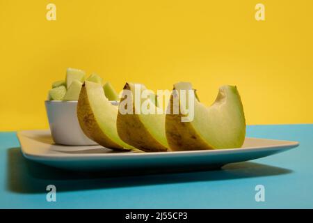 Sliced melon on a plate. Yellow and blue background. Stock Photo